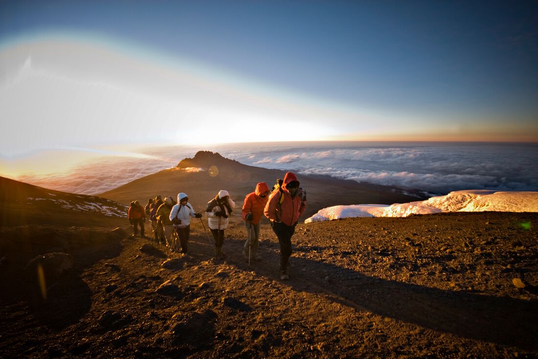 Travellers in a line approaching the peak of Kilimanjaro in Tanzania