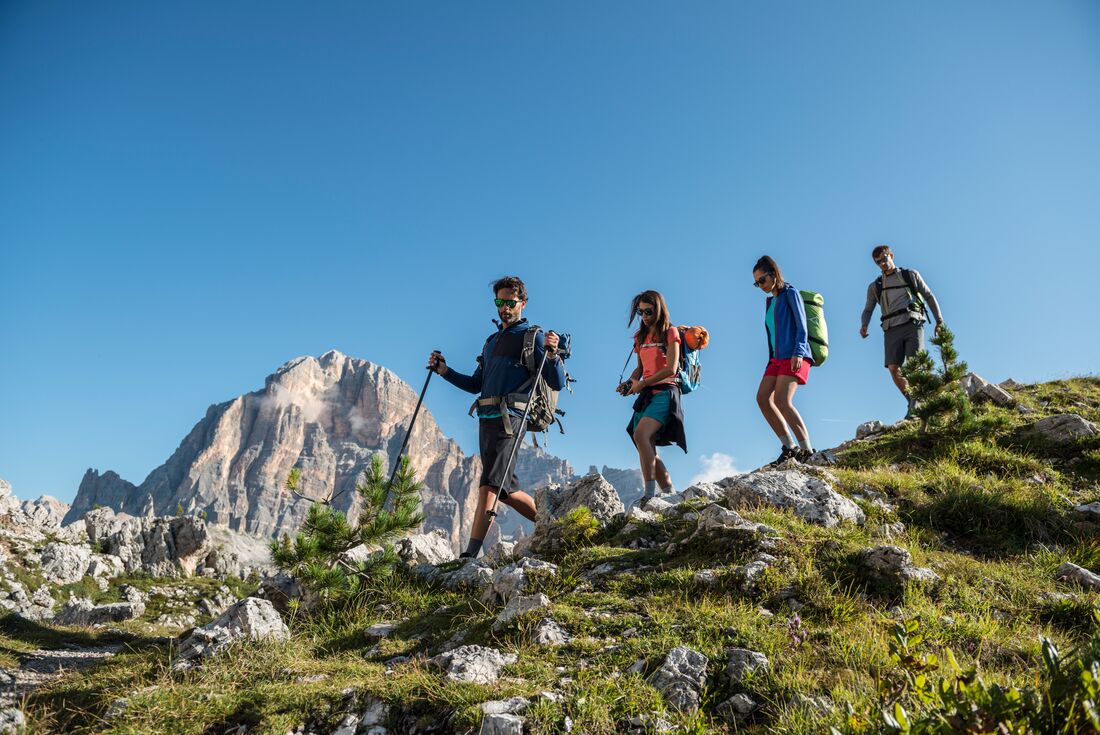 Group of travellers descending a hill with various hiking gear in the Italian Dolomites